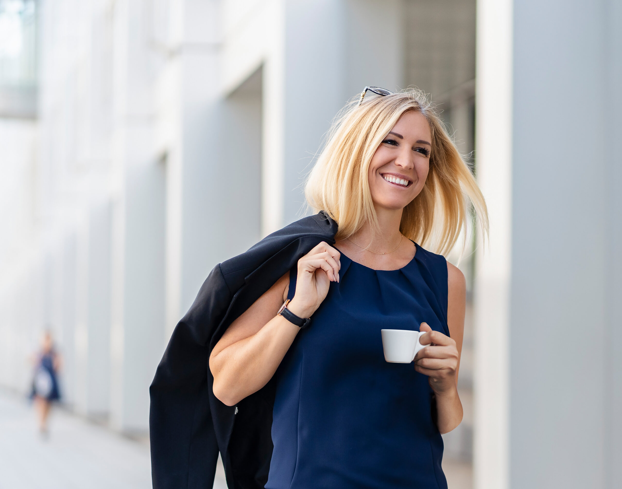 Portrait of smiling blond businesswoman with coffee to go wearing blue summer dress